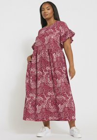 Kastanjebrun blommig maxiklänning med korta volangärmar, åtsittande under bysten. Tillverkad av lätt material och har ett mönstrat design.