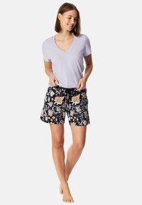 Lichte lavendel v-hals t-shirt gecombineerd met zwarte shorts met kleurrijke bloemenpatronen en een trekkoordtaille. Zacht materiaal, ontspannen pasvorm.