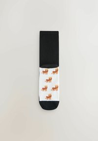 Zwart-witte sokken met een speels patroon van kleine bruine leeuwen, met details op een gladde textuur. De vezels lijken zacht en rekbaar.