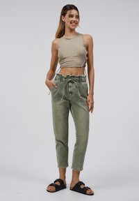 Lichtgroene, gestructureerde katoenen joggerbroeken met een elastische tailleband en trekkoord. Gecombineerd met een beige korte tanktop en zwarte sandalen.