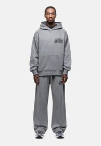 Grijze sweatshirt en bijpassende sweatpants van zacht materiaal. Capuchonontwerp met een voorzak; bevat geprinte tekst op beide items.