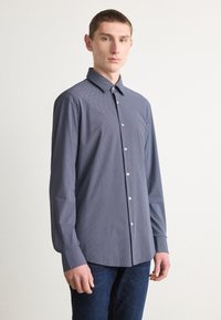 Camicia button-up blu navy con un motivo geometrico, maniche lunghe e colletto classico. Realizzata in un tessuto liscio con una vestibilità rilassata.