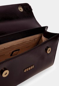 Borsa a mano in ecopelle color granata con accessori dorati, dotata di interno foderato e più scomparti, inclusa una sezione con cerniera e marchio distintivo.