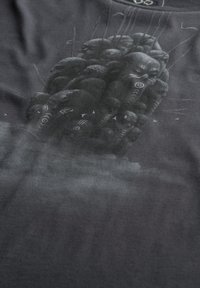 Donkergrijze T-shirt met een gedetailleerde illustratie van gezichten en symbolen, met een zachte textuur en een ronde halslijn.