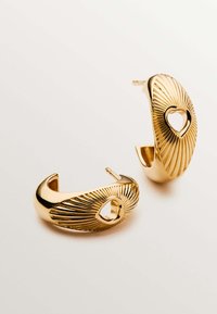 Pendientes dorados con un diseño curvado que presenta líneas radiales y recortes en forma de corazón. Textura lisa con un acabado reflectante.