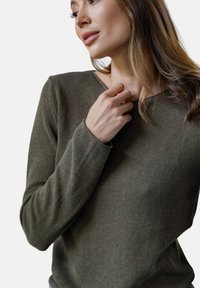 Sweter w kolorze oliwkowym, dzianinowy, prążkowany, z okrągłym dekoltem i długimi rękawami, charakteryzujący się delikatną teksturą i dopasowanymi mankietami.