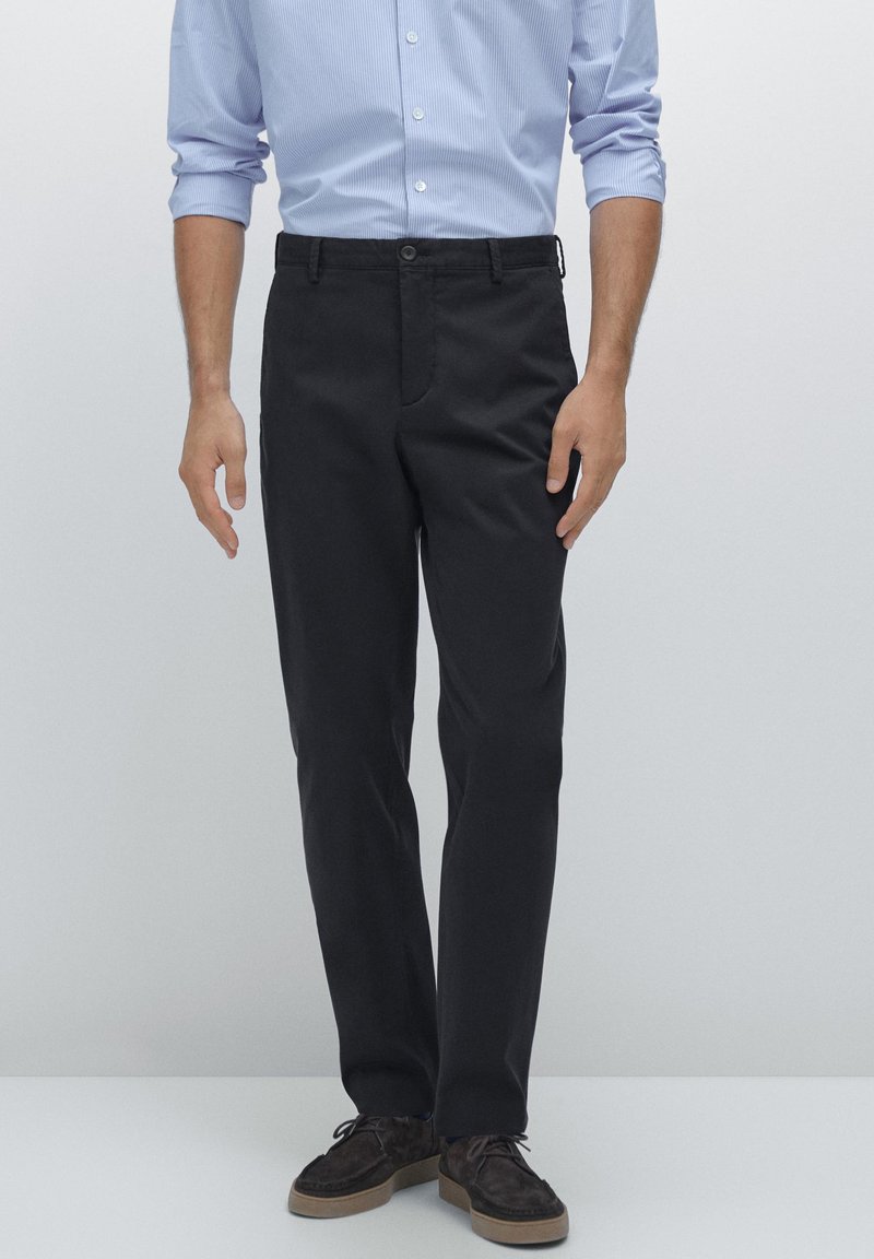 Black cotton chino pants with a flat front, belt loops, and a single button closure. Smooth texture, tailored fit, and straight leg design.