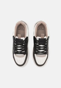 Sneaker bianche e nere con tomaia in pelle liscia, punta tonda, dettagli perforati e lacci a contrasto. Fodera interna morbida e logo.