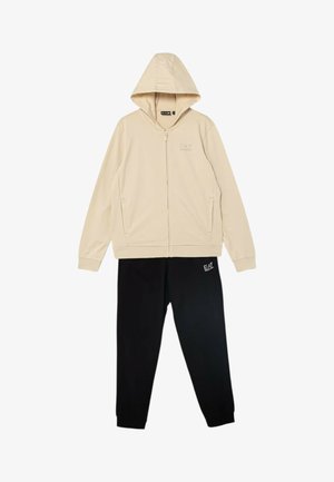 Felpa beige con cappuccio e zip integrale con tasche abbinata a pantaloni della tuta neri, entrambi con i loghi EA7 Emporio Armani.