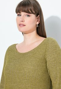 Olivgrüner gerippter Pullover mit weitem Rundhalsausschnitt, kontrastierendem Texturmuster und subtiler Sheen. Lange Ärmel mit figurnaher Passform.