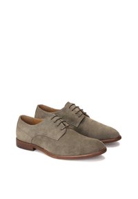 Chaussures en suède grises avec un bout rond et des lacets marron. Elles présentent un talon bas en cuir marron et une doublure intérieure lisse.