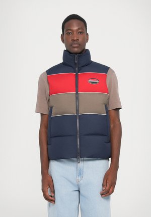 Padded vest featuring red, navy, and taupe color blocks, high collar, zip closure, and logo patch on the chest. Cotton blend fabric.