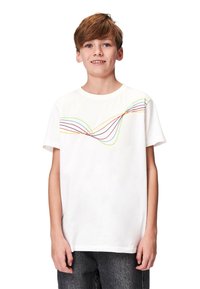 Vit bomull T-shirt med flerfärgade svängda linjer över bröstet. Kortärmad och avslappnad passform. Matchad med mörk denimbyxor.