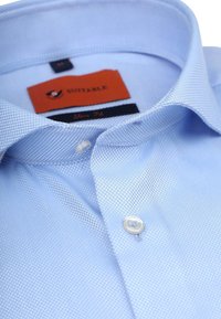  Lichtblauw, slim-fit shirt met een gestructureerd patroon, knoopsluiting, en een merklabel met oranje en donkerblauwe accenten.