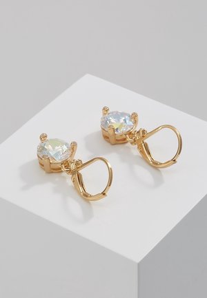 Gold lever-back earrings with round, clear faceted gemstones set in four-prong settings on white display surface.
