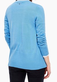 Světle modrý pletený svetr s dlouhými rukávy, ribbenou strukturou a kulatým výstřihem. Obsahuje malé logo na zadní straně a má uvolněný střih.