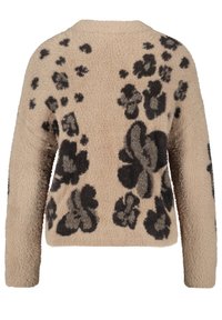 Pull beige en peluche avec des motifs floraux noirs, manches longues et col rond. Texture douce et coupe décontractée.