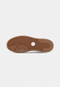 Semelle de chaussure avec motif en caoutchouc marron comportant des motifs en losange et circulaires et un petit logo blanc rond au centre.