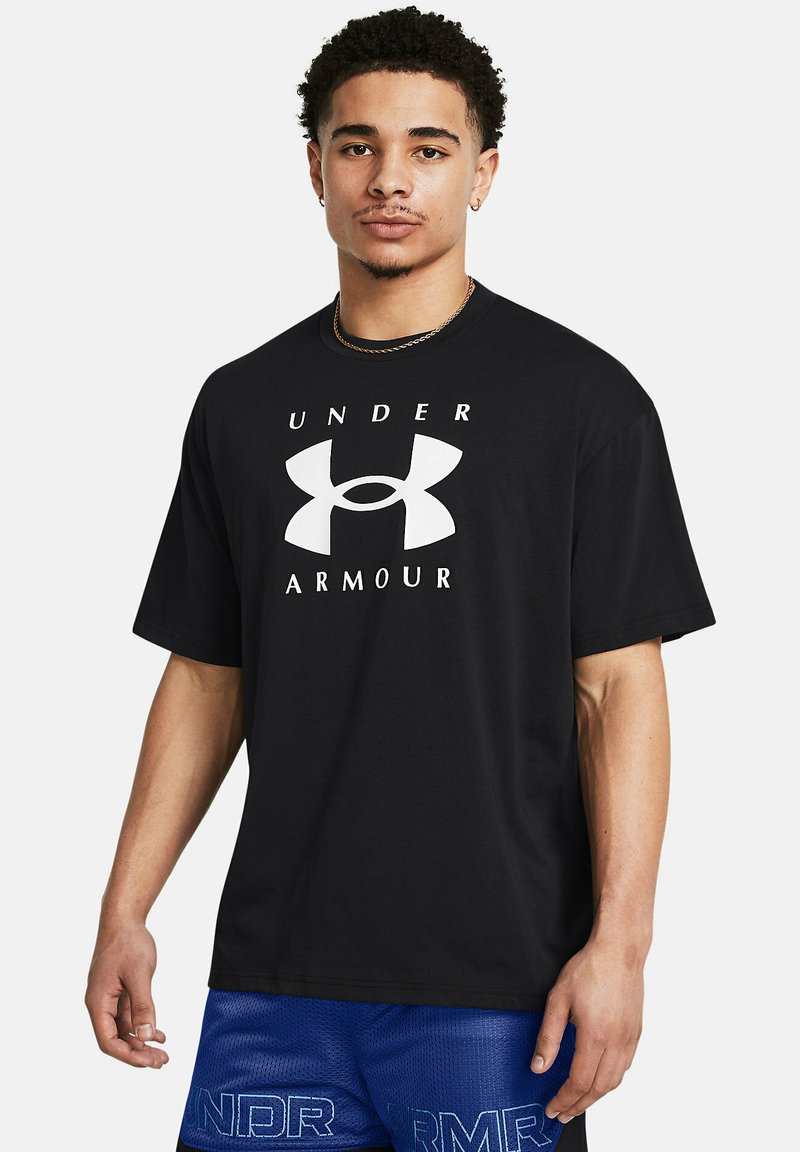 Juodas trumpomis rankovėmis T-shertas, ant krūtinės didelis baltas Under Armour logotipas. Audinys atrodo lygus; laisvas kirpimas.