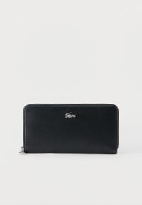 Μαύρο πορτοφόλι από υφή δέρματος με φερμουάρ και ασημένιο λογότυπο κροκοδείλου στο κέντρο μπροστά πάνω σε απλό λευκό φόντο.