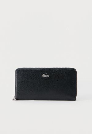 Melnas teksturētas ādas maks ar rāvējslēdzēju apkārt, priekšā centrā sudraba krokodila logotips uz vienkārša balta fona.