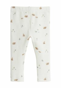 Vita, snug leggings med ett texturerat tyg som har ett upprepande mönster av små bruna björnar och gröna blommiga accenter genom hela plagget.