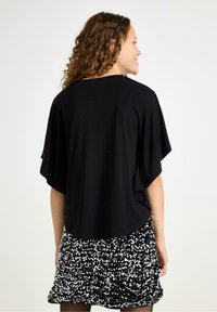 Black, short-sleeve top paired with a ruffled skirt covered in silver and black sequins, featuring a loose fit and soft texture.