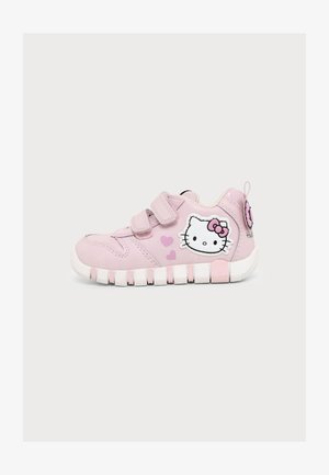 Różowy dziecięcy sneaker z dwoma paskami na rzepy, białą podeszwą oraz wzorami twarzy i serca Hello Kitty z boku i z tyłu.