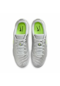 Nike Tiempo shoes featuring a silver and grey synthetic upper, textured design, and vibrant green insole with contrasting laces and accents.
