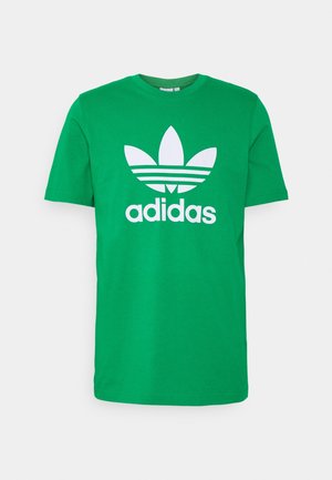 Zielona koszulka Adidas z krótkim rękawem z dużym białym logo trefoil i tekstem "adidas" na środku z przodu.