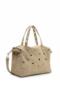 Bolso de ante beige con recortes circulares y ojales metálicos. Cuenta con dos asas y una correa de hombro desmontable. Cierre con cremallera.