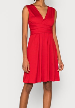 Rotes ärmelloses Kleid mit tiefem V-Ausschnitt und tailliertem Oberteil, das an der Taille geraffte Details und einen fließenden Rock aufweist. Glatte Stoffstruktur.