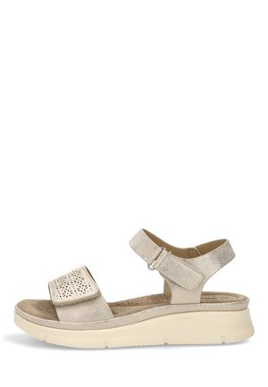 Sandalia beige con puntera abierta, correa ajustable y diseño perforado, plantilla acolchada y suela blanca gruesa.