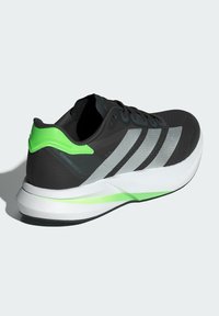 Čierna bežecká obuv so striebornými pruhmi, zelenými akcentmi na päte a jazyku, textúrovaný zvršok, ľahká medzipodošva a gumová podrážka.