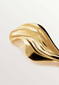 Objeto de metal dorado con curvas suaves y fluidas y una superficie brillante, que se asemeja a una ola o a una escultura abstracta. Texturizado con acentos reflectantes.