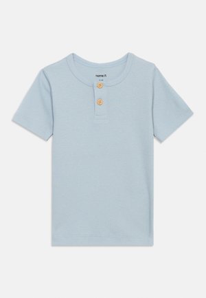 Lichtblauw ribgebreid peutershirt met korte mouwen, ronde halslijn en twee houten knopen op de voorplacket.