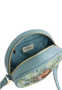 Borsa rotonda in pelle blu con ricami floreali, zip dorata e tasca interna. Presenta una texture liscia e una tracolla regolabile.