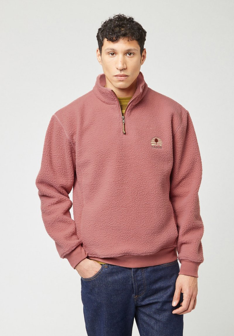 Fleece pullover in stoffige rozenkleur, met een halve ritssluiting aan de voorkant, geribbelde manchetten en een gestructureerd oppervlak. Logo patch op de borst.