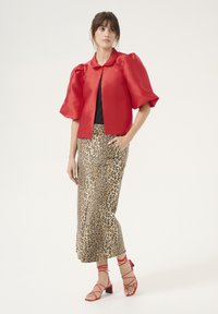 Red satin cropped jacket with puff sleeves, paired with a leopard-print skirt and red strappy block-heeled sandals. Black top underneath.
