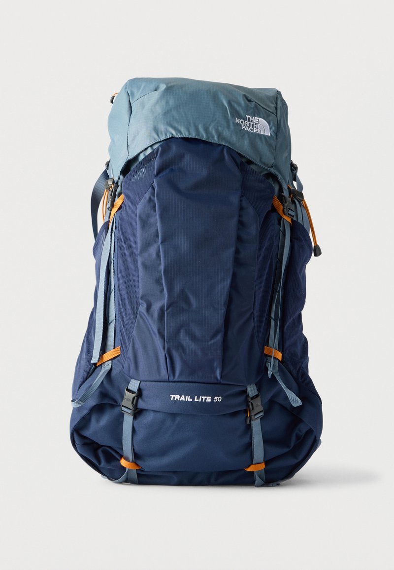 Velký modrošedý turistický batoh North Face Trail Lite 50 s mnoha popruhy a oranžovými akcenty