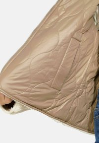 Bežová prešívaná bunda s jemným krémovým fleece podšívkou. Zipsový uzáver a bočná vrecko. Hladký povrch, teplý dizajn.