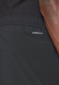 Svarta shorts med elastisk midja och vit "AEROREADY"-logotyp, med en slät textur och lätt tyg.