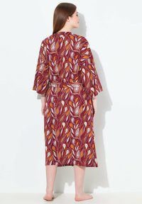 Fialový župan s živým paisley vzorem v oranžové a bílé. Má široké rukávy a vázací pas pro uvolněný střih.