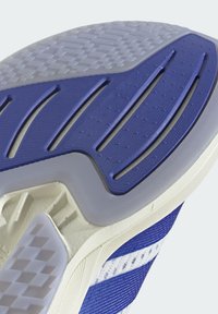Suela de zapato deportivo con goma azul, patrones texturizados y acentos blancos. Presenta ranuras para tracción y un diseño en capas para estabilidad.