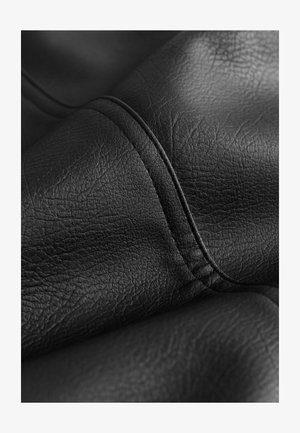 Čierna koženka so viditeľnou textúrou; má hladký povrch a jemné vrásky. Švy sú prešité zodpovedajúcou niťou.