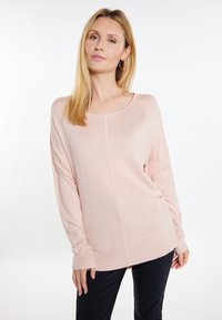 Pulover roz deschis cu gât rotunjit, mâneci lungi, tiv ribbed și slituri laterale. Textură moale și croială lejeră.