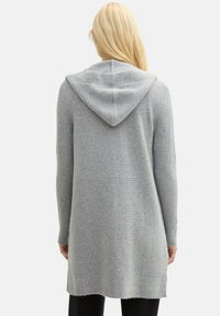 Grå lång kofta med huva, med ribbat mönster på ärmarna och en slät kropp. Enkelt design utan synliga mönster eller accenter.