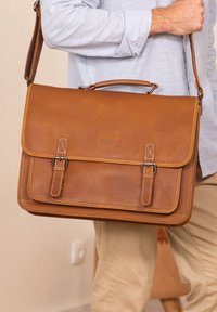 Brun læder messenger taske med låg, to spænder og dobbeltsyning. Har en top håndtag og justerbar skulderrem.