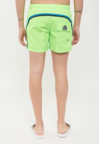 Costumi da bagno verde neon realizzati in materiale leggero, con strisce laterali nere e blu, una tasca posteriore e un logo sulla cintura.