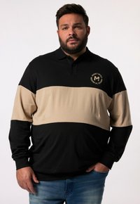Černé a béžové polo triko s dlouhým rukávem a límečkem, s horizontálním barevným blokováním a kulatým logem na hrudi.